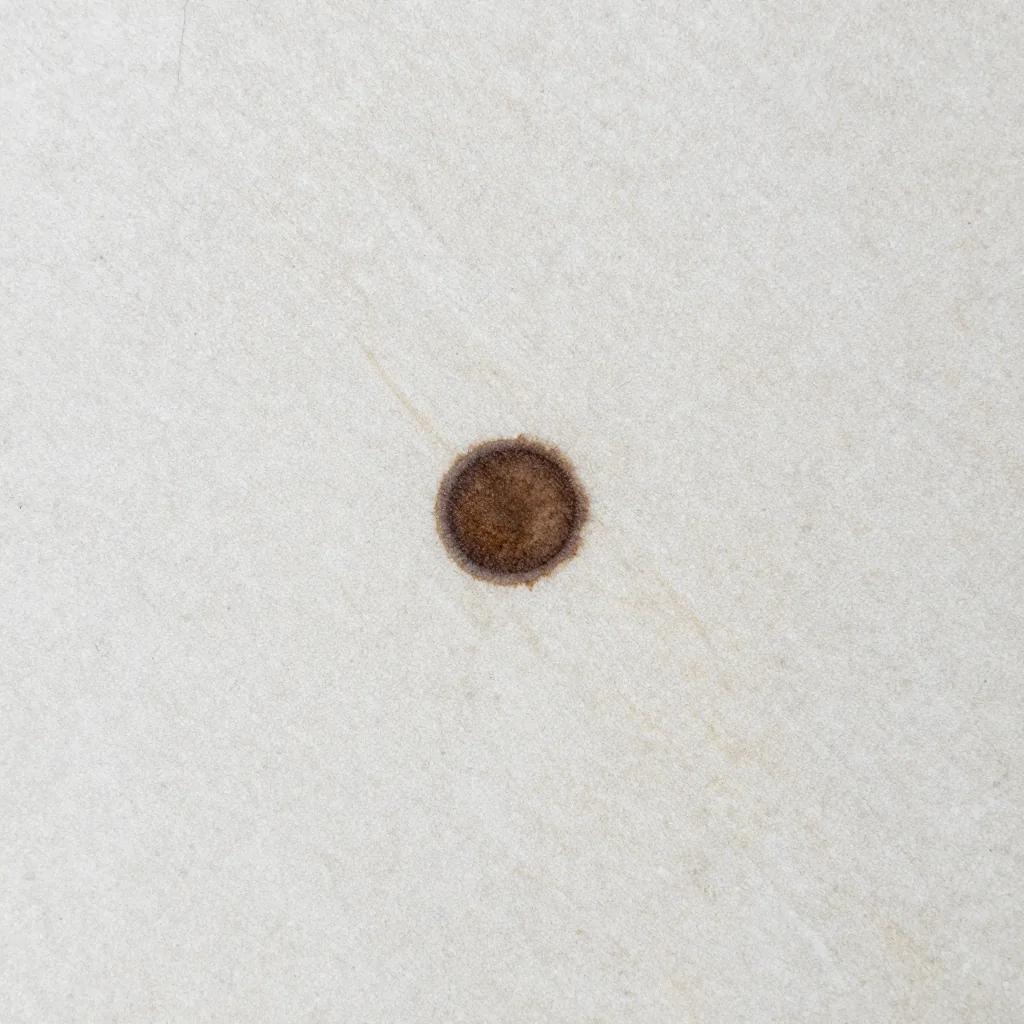 Synthetic limestone tabletop with a central brown stain